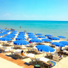 Spiaggia con ombrelloni blu e sedie a sdraio.