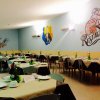 Sala ristorante con tavoli apparecchiati e murali sulle pareti.
