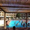 Persone che nuotano in piscina, ombrelloni in lontananza.