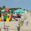 Area giochi per bambini sulla spiaggia con scivoli e ombrelloni.