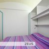 Camera da letto con pareti bianche e letto con copriletto a righe colorate.