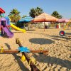 Parco giochi colorato su sabbia con scivoli e giostre.