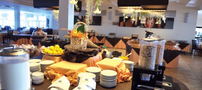 Sala buffet con tavoli apparecchiati e decorazioni appese.