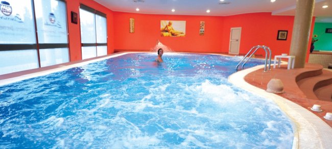 Piscina coperta con pareti arancioni e persona che nuota.