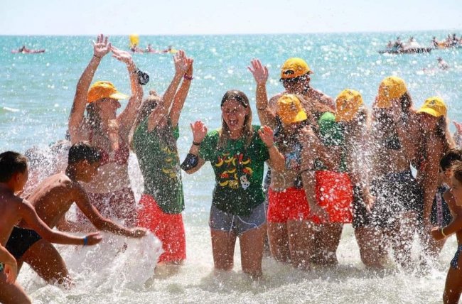 Gruppo di persone che giocano in mare, spruzzi d'acqua.
