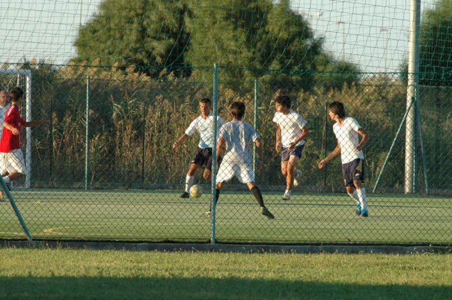 Ragazzi giocano a calcio su un campo all'aperto.