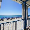 Spiaggia con ombrelloni blu vista da una veranda di legno.