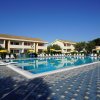 Una piscina con lettini e ombrelloni davanti a edifici.