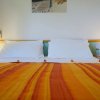 Letto matrimoniale con lenzuola bianche e coperta a strisce arancioni.
