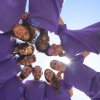 Gruppo di persone in cerchio con maglie viola.