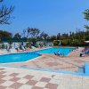 Piscina con bagnanti, circondata da sedie a sdraio.