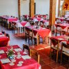 Sala da pranzo con tavoli apparecchiati di rosso.