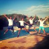 Quattro persone saltano felici accanto a una piscina.