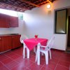 Cucina all'aperto con tavolo e sedie bianche.