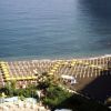 Spiaggia affollata con ombrelloni gialli e lungomare.
