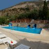 Piscina con scivoli blu, sedie a sdraio e vista su colline rocciose.