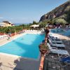Piscina con sedie a sdraio, scivolo blu e montagna sullo sfondo.