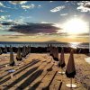 Spiaggia al tramonto con ombrelloni chiusi.