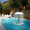 Piscina con fontana a fungo e sdraio bianche.