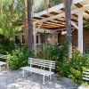 Panchine bianche tra alberi e vegetazione.