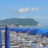 Ombrelloni blu su spiaggia con mare e montagna.
