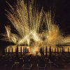 Fuochi d'artificio dorati sopra il mare di notte.