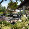 Sedie e tavoli neri in un giardino fiorito sotto alberi.