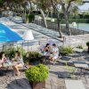 Persone sedute a tavoli all'aperto vicino a una piscina e un campo da tennis.