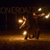 Giocolieri con fiamme si esibiscono di notte su una spiaggia.