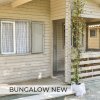 Bungalow beige con veranda e piante rampicanti.