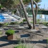 Terrazza con sedie e tavolini vicino a piscina e campo da tennis.