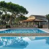 Piscina con riflessi di alberi, vicino a un edificio con tetto in tegole.