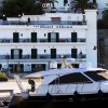 Un hotel bianco a tre piani vicino a una barca al molo.