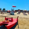 Spiaggia con pedalò rosso e lettini.