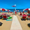 Spiaggia con sdraio e ombrelloni rossi e bianchi.