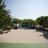 Spiazzo con palco sotto un arco, circondato da alberi.