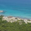 Spiaggia con mare turchese e vegetazione lussureggiante.