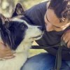 Uomo affettuoso con cane bianco e nero al parco.