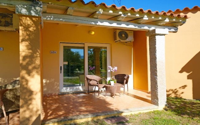 Portico con tavolino e sedie, ingressi con ampie porte vetrate.